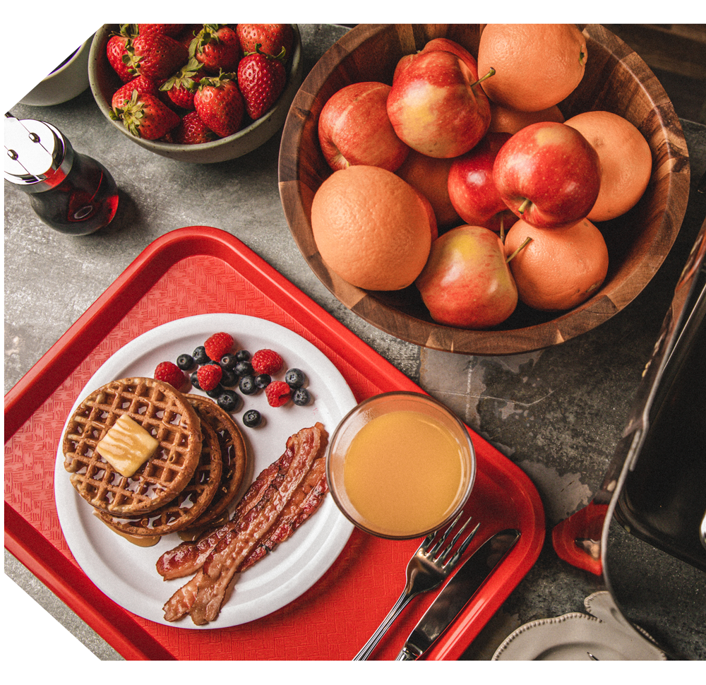 Kodiak Food Service - a dining tray with toaster waffles, bacon, fruit and orange juice